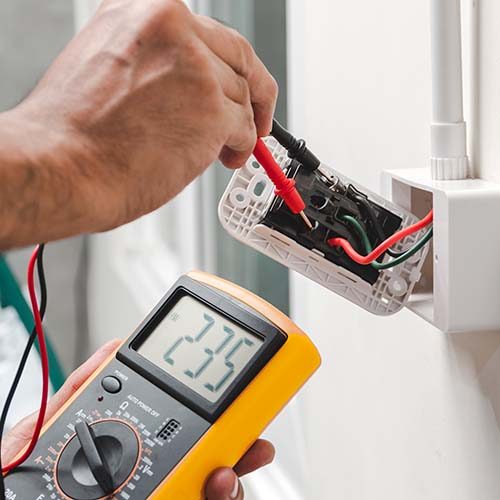 technology in home Electrician is using a digital meter to measure the voltage at the power outlet in on the wall.